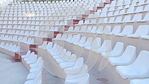 White chairs of an empty amphitheater or stadium under the open sky. A row of seats without spectators