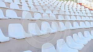 White chairs of an empty amphitheater or stadium under the open sky. A row of seats without spectators