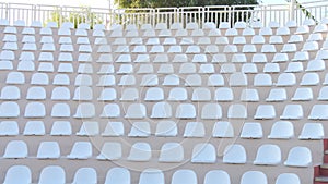 White chairs of an empty amphitheater or stadium under the open sky. A row of seats without spectators