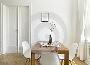 White chairs at wooden table in minimal dining room interior wit