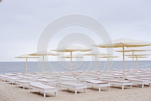 White chaise lounges and umbrellas by the sea at dawn, romantic time
