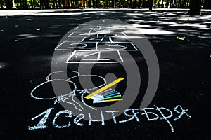 White chalk on black asphalt inscription in Russian September 1. yellow line, colorful markers, painted balls,hopscotch