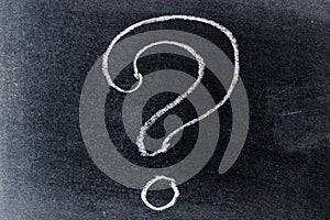 White chalk drawing in questionmark shape on black board background