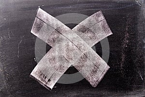 White chalk hand drawing in cross or x shape on blackboard background