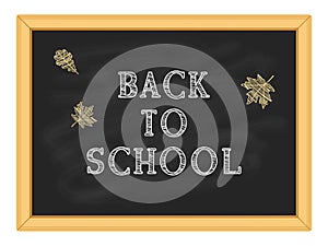 White chalk inscription Back to school and yellow autumn foliage on a blackboard in a wooden frame