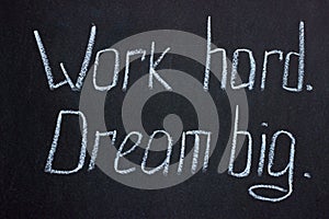 White chalk writing on a dark board `Work hard. Dream big.` photo