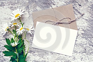 White chamomile flowers and blank white greeting card with envelope