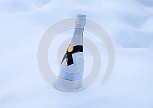 a white champagne bottle buried in the white frosty snow ready for part celebrate season\'s greetings