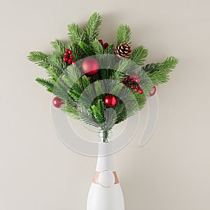 White champagne bottle with fir branches and Christmas decorations. Minimal party concept.