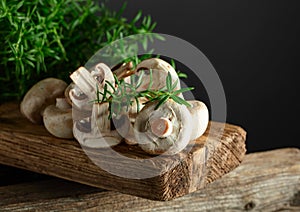 White champignons with rosemary on a wooden board