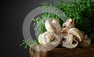 White champignons with rosemary on a wooden board