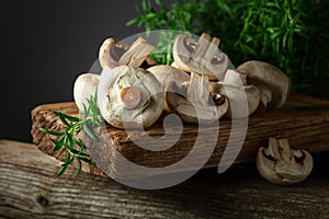 White champignons with rosemary on a wooden board