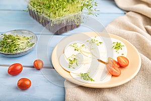 White cheese with tomatoes and cilantro microgreen on blue. side view, selective focus