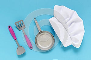 White chef hat on the blue background with kiddish toy utensils. photo