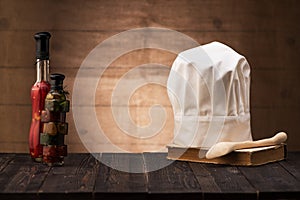 White chef`s hat and old cookbook on the kitchen table
