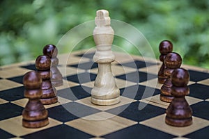 White chess king surrounded by black pawns