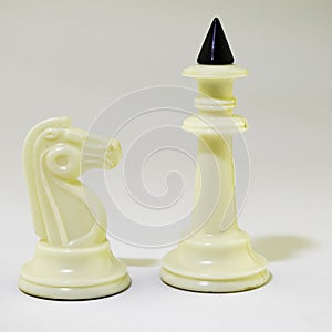 White chess knight and white chess king stand on a white background, rigid shadow