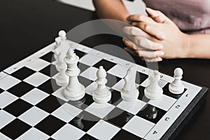 White chess pictures laid out on a chessboard, concept comparing playing chessboard to business administration.