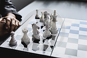 White chess pictures laid out on a chessboard, concept comparing playing chessboard to business administration.