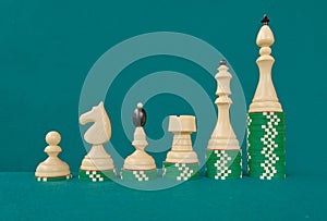 White chess pieces on green felt background, ordered by their increasing value.