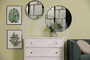 White chest of drawers with lamp and mirrors on wall in room. Interior design