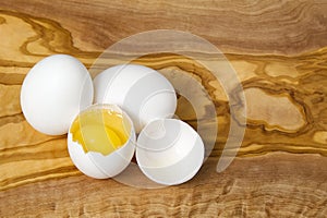 White chicken eggs and broken eggs on wooden board or table. close up