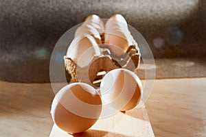 White chicken eggs in cardboard on wooden surface with interesting light. The concept of taking pictures of food. Fresh eggs from