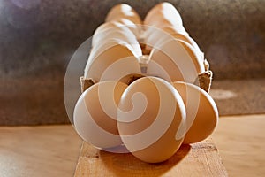 White chicken eggs in cardboard on wooden surface with interesting light. The concept of taking pictures of food. Fresh eggs from