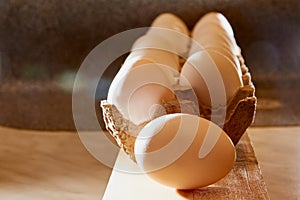 White chicken eggs in cardboard on wooden surface with interesting light. The concept of taking pictures of food. Fresh eggs from