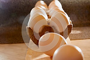 White chicken eggs in cardboard on wooden surface with interesting light. The concept of taking pictures of food. Fresh eggs from