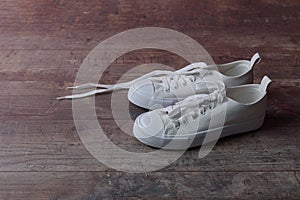 White children sneakers on a old textured wood background