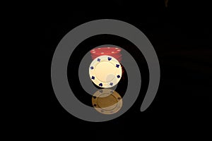 White chips stack with a red chip in front isolated on black with reflection