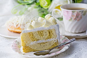 White choclate cake wiyh beautiful cup of coffe on white table and flower photo