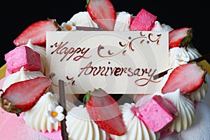 White chocolate anniversary greeting card on top of strawberry mousse cake