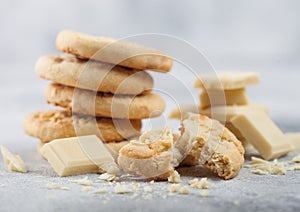 White chocolate biscuit cookies with chocolate blocks and curls on light kitchen table background