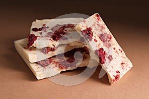 White chocolate with freeze dried raspberries on brown table, closeup