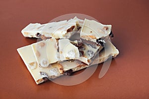 White chocolate with nuts, raisins on a brown background