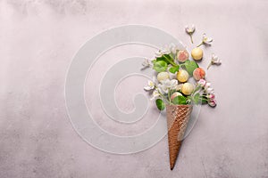 White chocolate truffle candy flowers waffle cone ice cream on gray concrete background. Horizontal frame copy space.