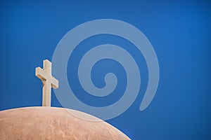 White Christian cross in front of a blue sky with copyspace