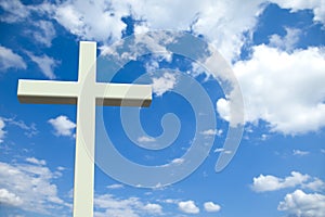 White Christian cross in front of a cloudy sky