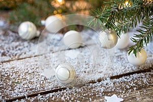 White Christmas balls, evergreens and snow on wooden underground