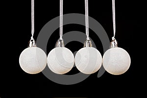White christmas balls hanging in a row on black background