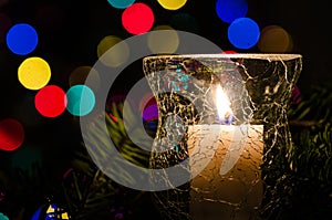 White Christmas Candle Surrounded by Christmas Lights and Evergreen Branches