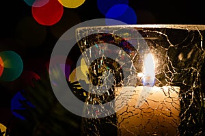 White Christmas Candle Surrounded by Christmas Lights and Evergreen Branches