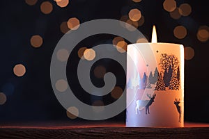 White Christmas candle on a wooden table with garlands background and winter themes