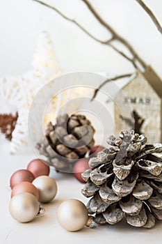 White Christmas decoration composition, big pine cones, scattered baubles, shiny rattan star, wooden candle holder