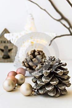 White Christmas decoration composition, big pine cones, scattered baubles, shiny star, wooden candle holder, dry tree branches