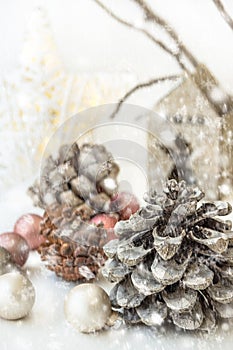 White Christmas decoration composition, pine cones, scattered baubles, shiny star, wooden candle holder, dry tree branches. Snow.