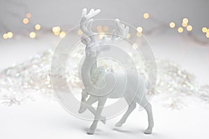 White Christmas decoration in scandinavian style with a reindeer, snow flakes and bokeh lights in the background