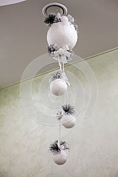 White Christmas decorations in the form of balls on a ribbon hang on the ceiling